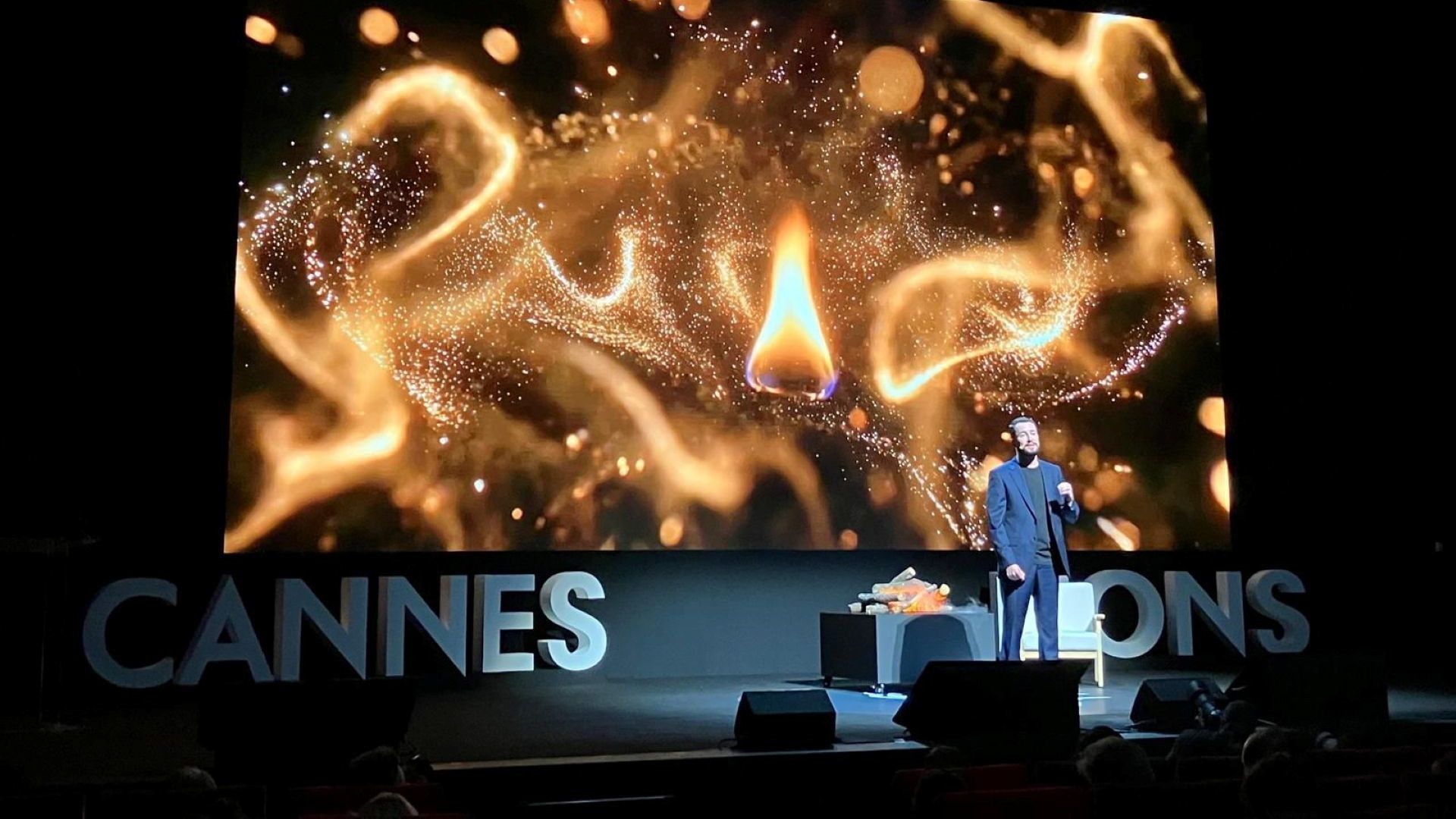 Leandro Barreto phát biểu trên sân khấu Cannes Lions, phía sau là hình ảnh những ngọn lửa