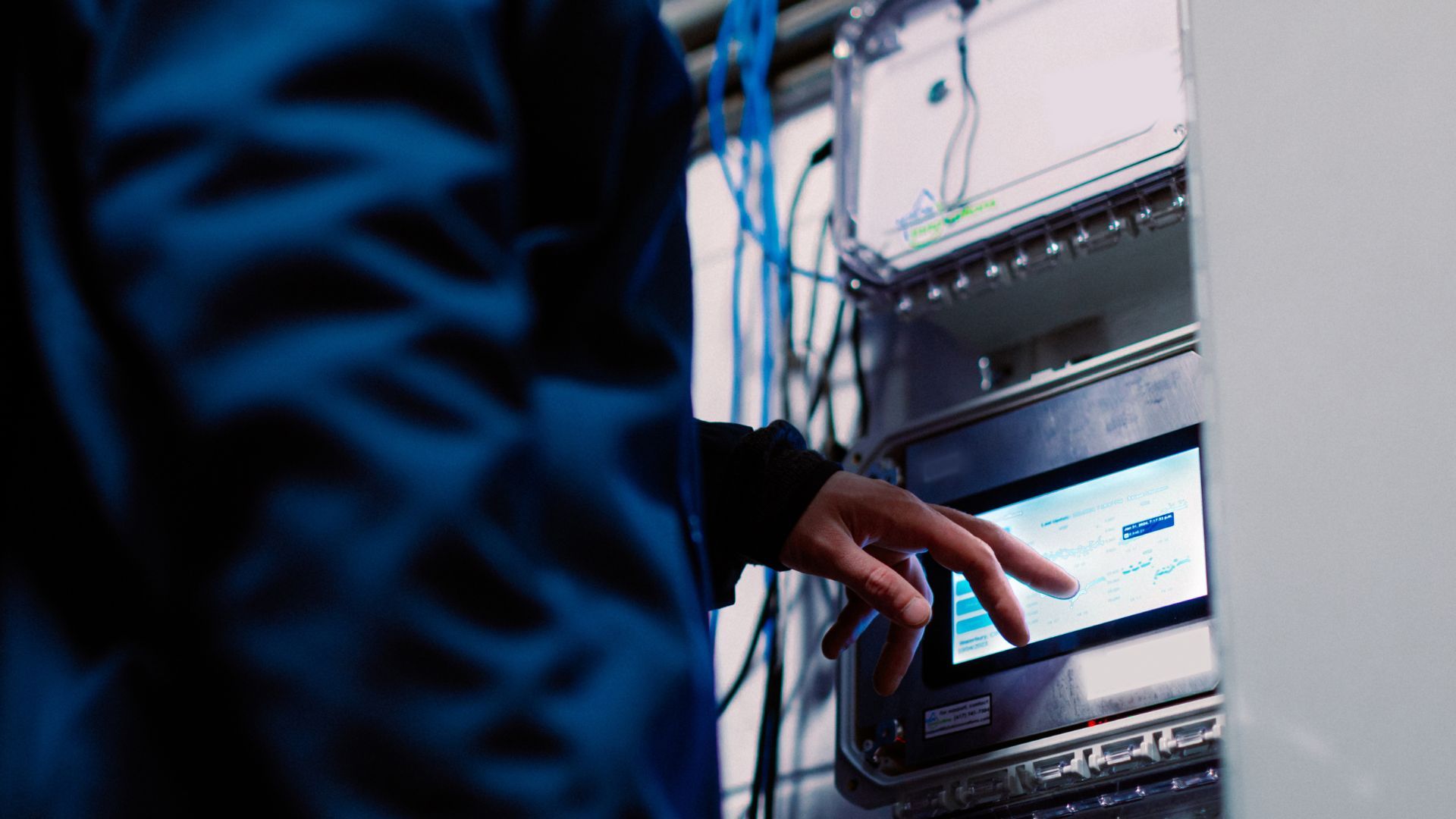 Công nhân nhà máy mặc đồng phục xanh hải quân đang chạm vào màn hình hiển thị dữ liệu sản xuất